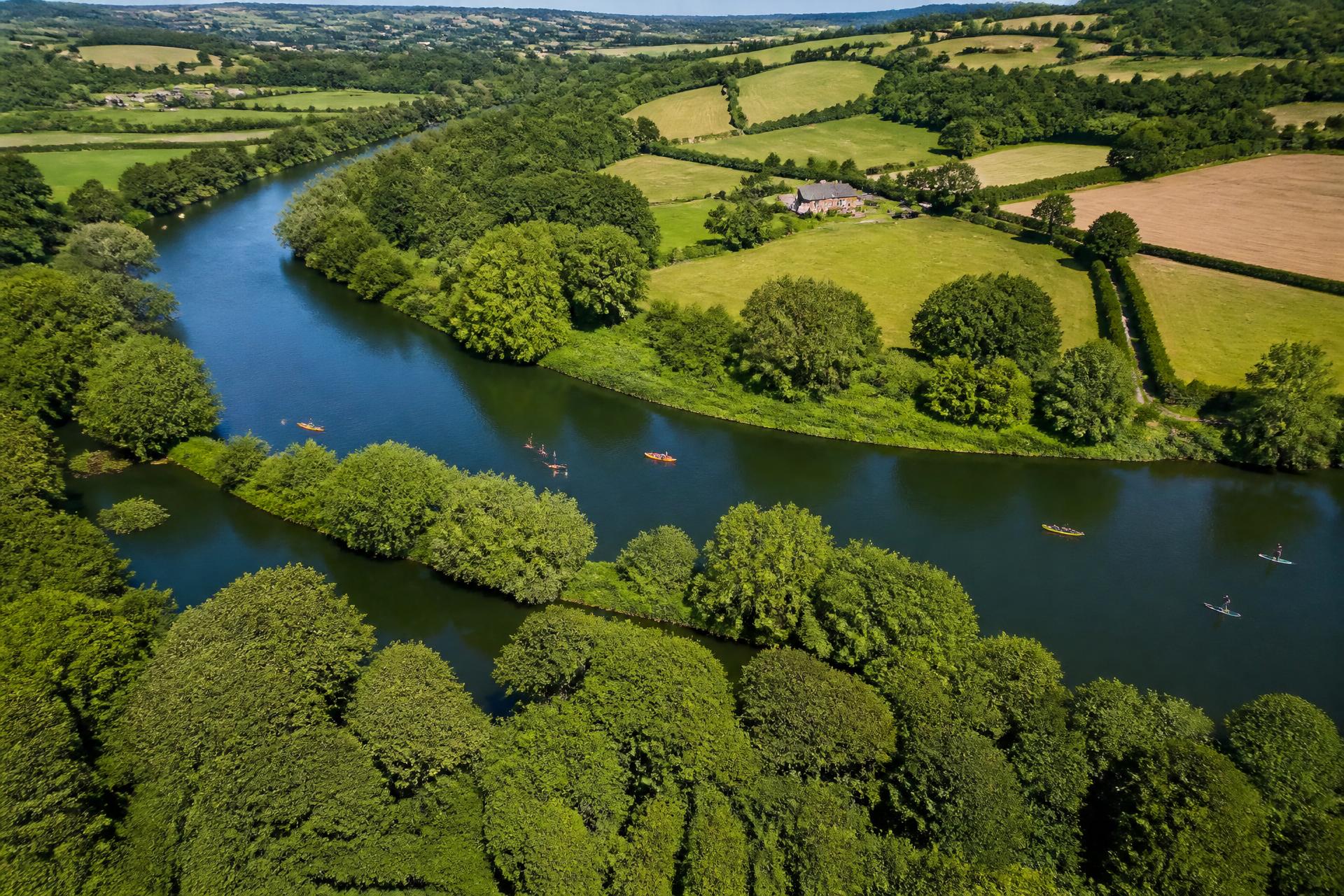Aerial view of the meandering River Severn between Hampton Loade and Upper Arley, running left to right through green Shropshire countryside with canoes and paddleboards on the water